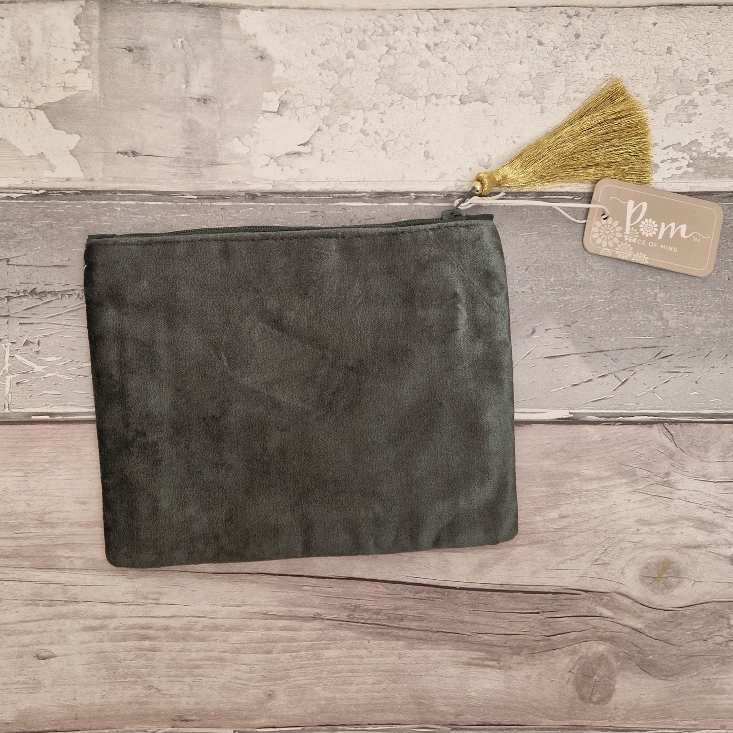 Dark gray suede pouch with a gold tassel on a wooden surface