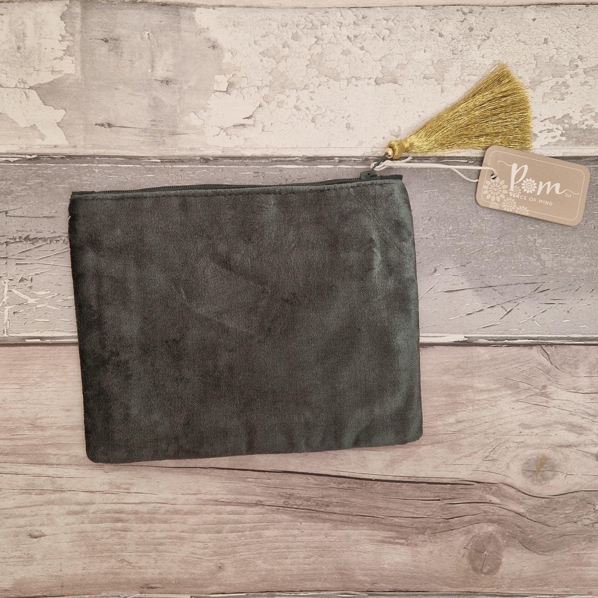 Dark gray suede pouch with a gold tassel on a wooden surface