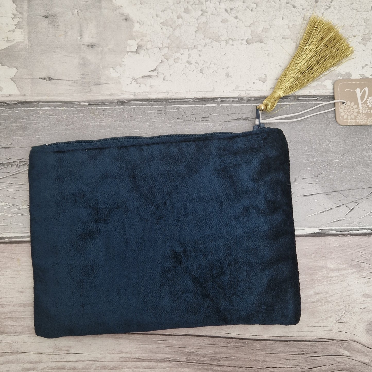 Dark blue pouch with a broom and tag on a wooden surface