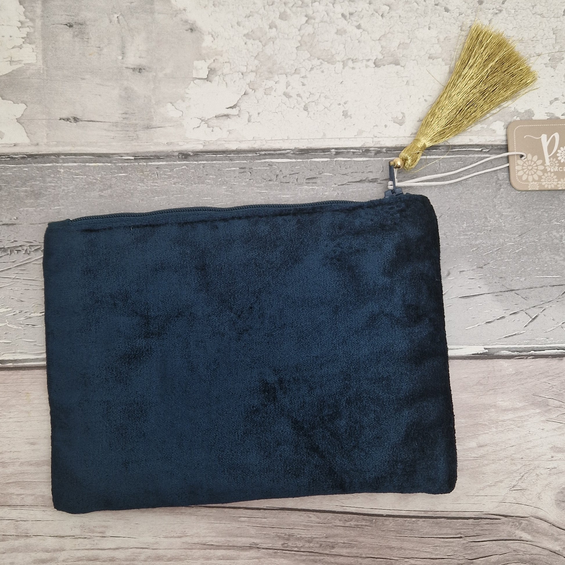 Dark blue pouch with a broom and tag on a wooden surface