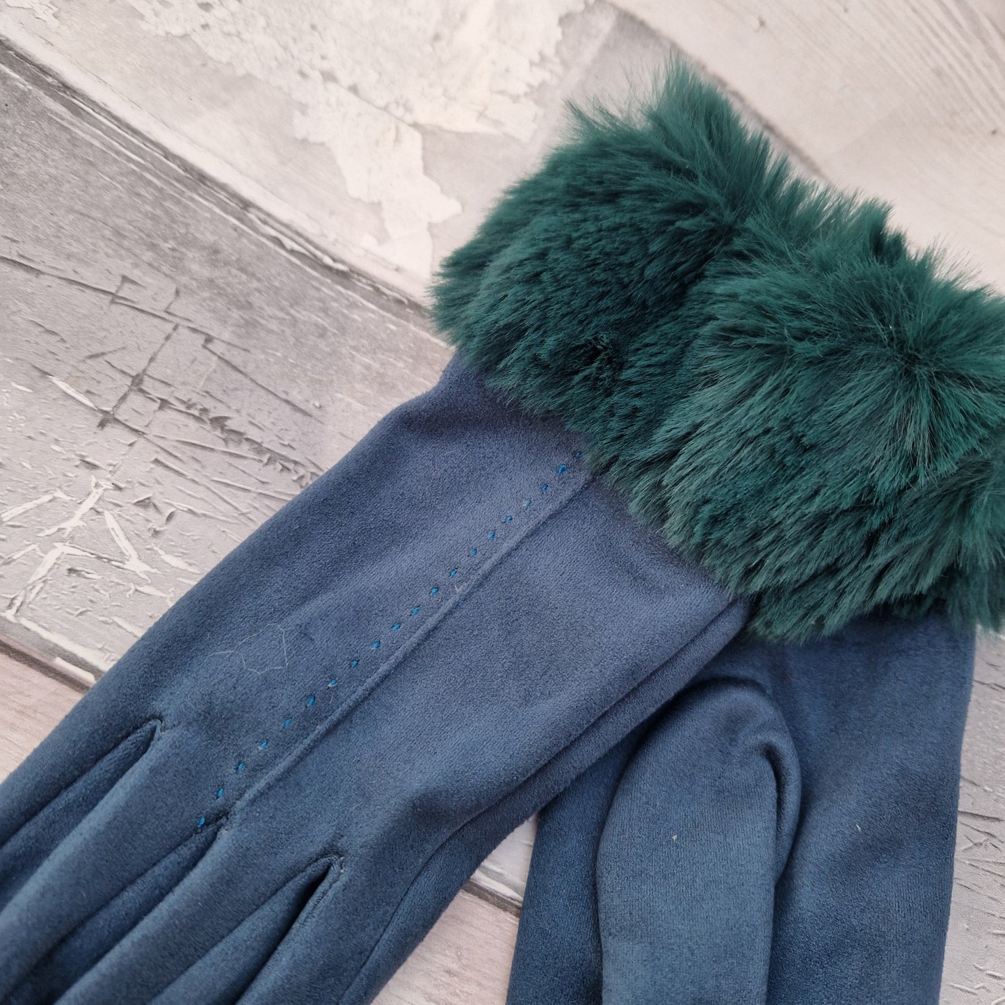 Teal coloured gloves with a faux fur trim and stitching detail down the back of the hand.