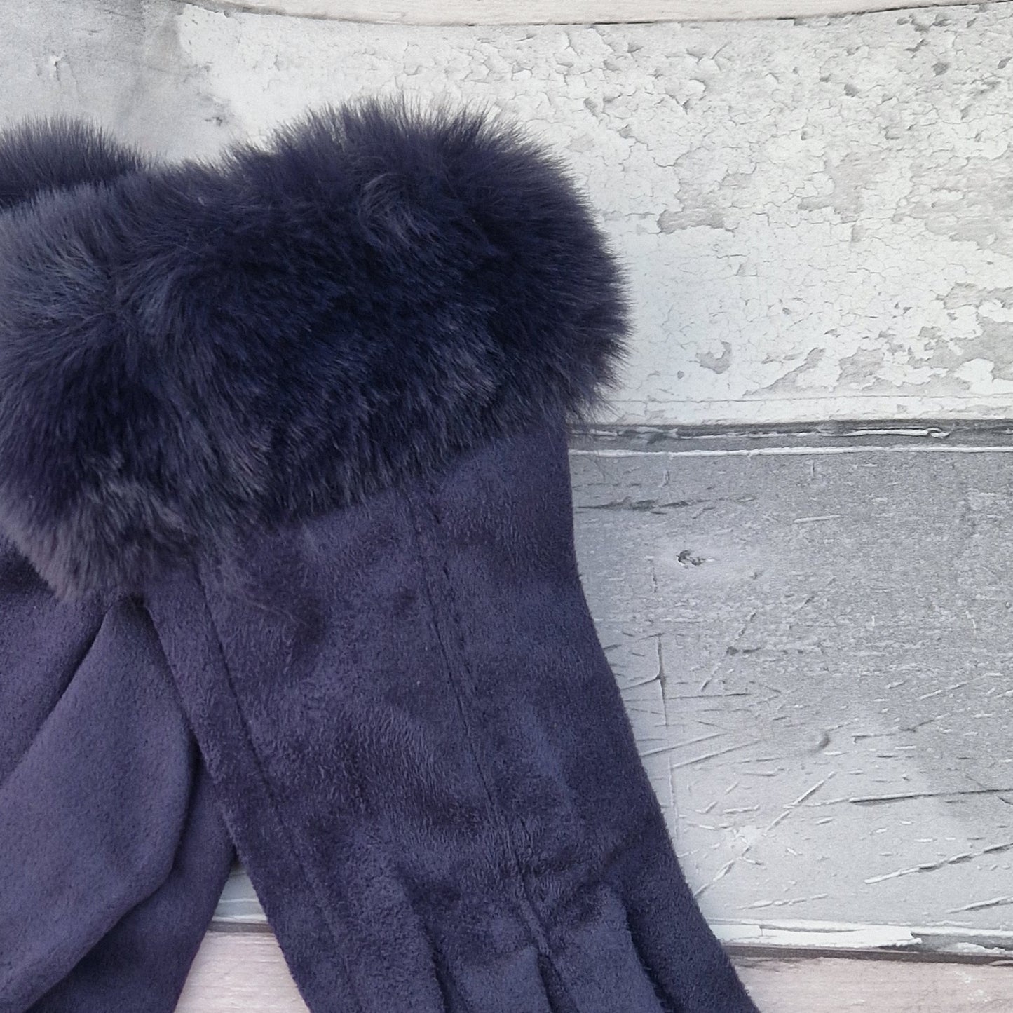 Navy coloured gloves with a faux fur trim and stitching detail down the back of the hand.