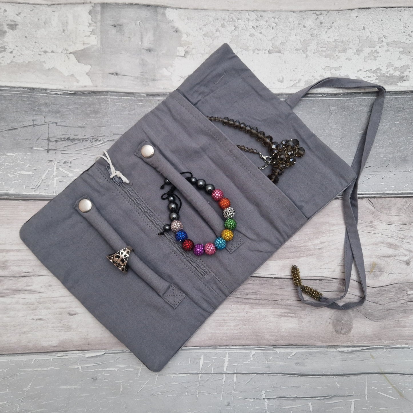 Inside view of a grey coloured jewellery roll with some sample jewellery pieces attached.