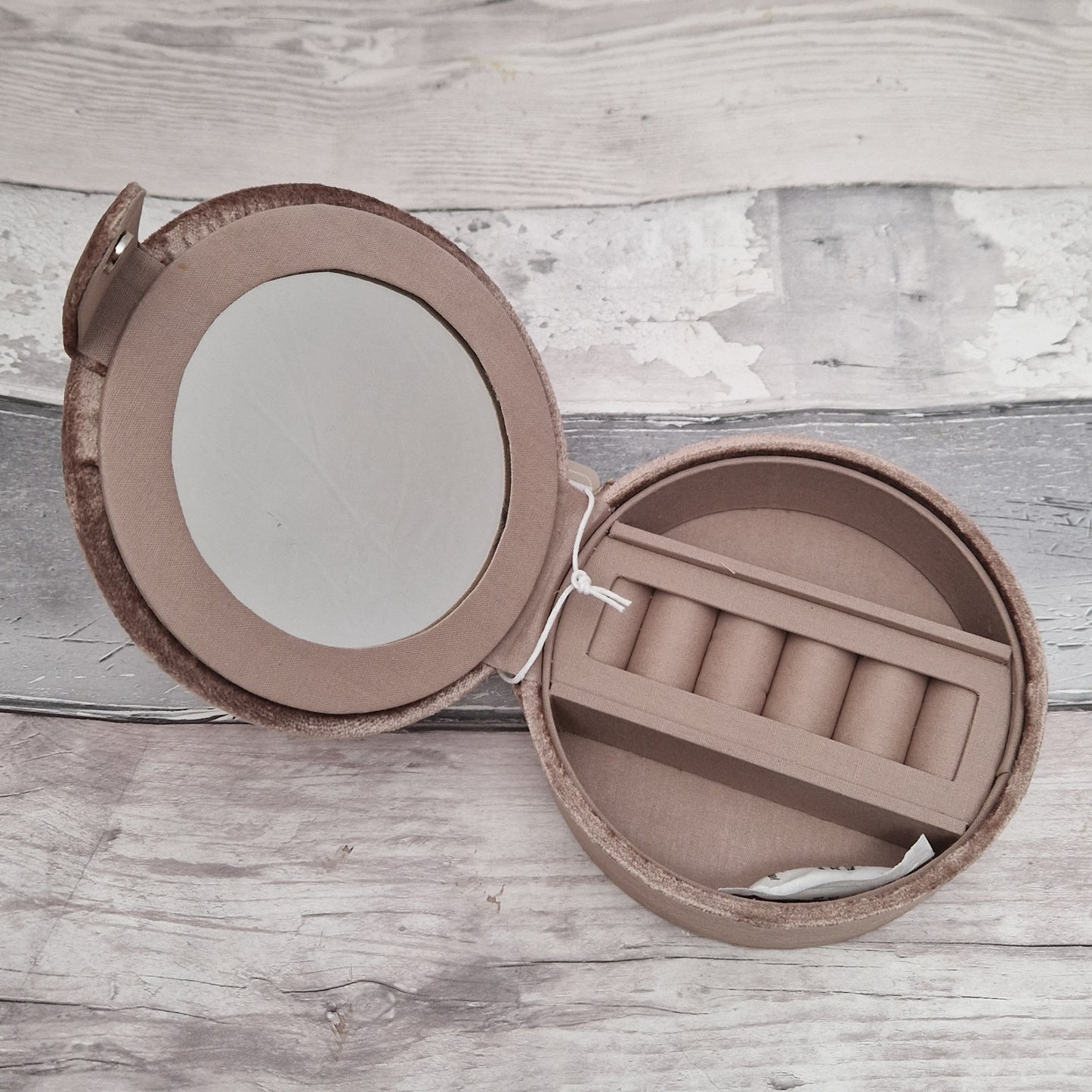 Round jewelry box with mirror on a wooden surface