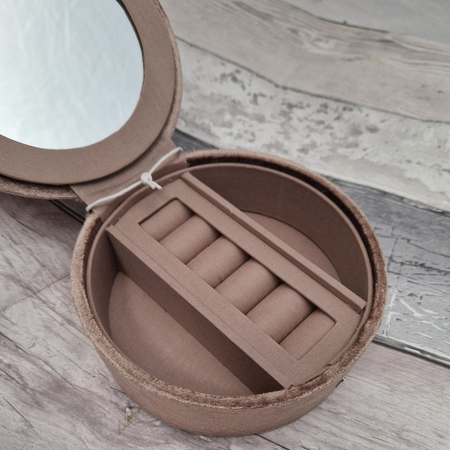 Round brown jewelry box with mirror on a wooden surface