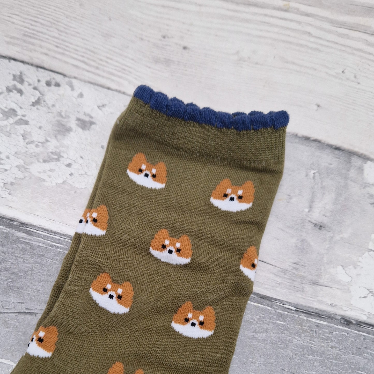 Green sock with corgi pattern on a wooden surface