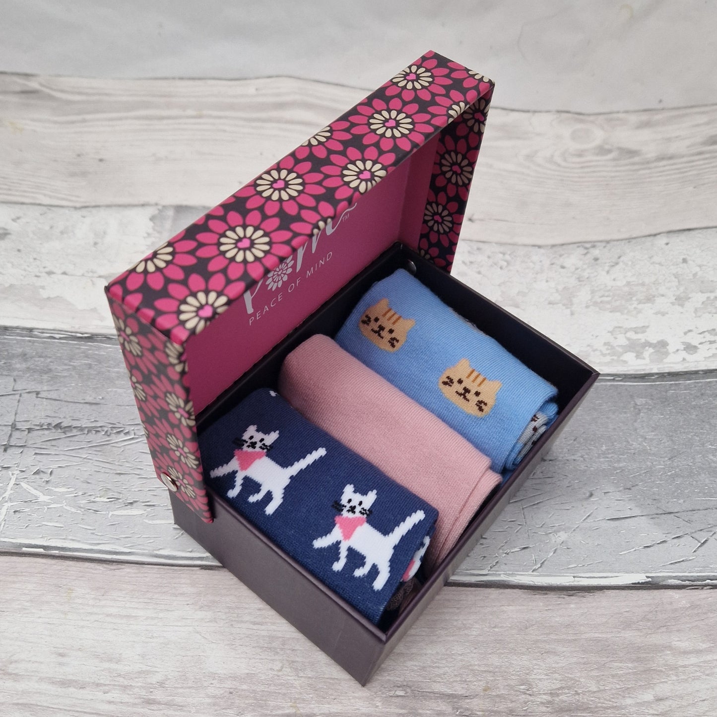 Three pairs of cat themed socks in a presentation gift box. Pink and blue colour scheme.