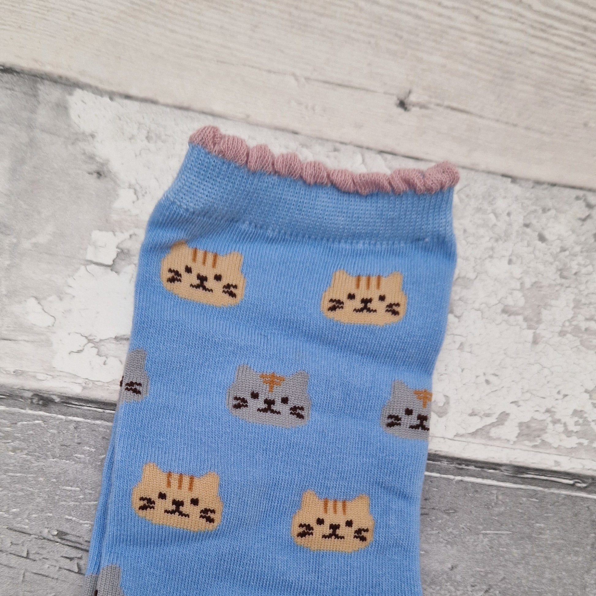 Blue sock with cat face patterns on a wooden surface
