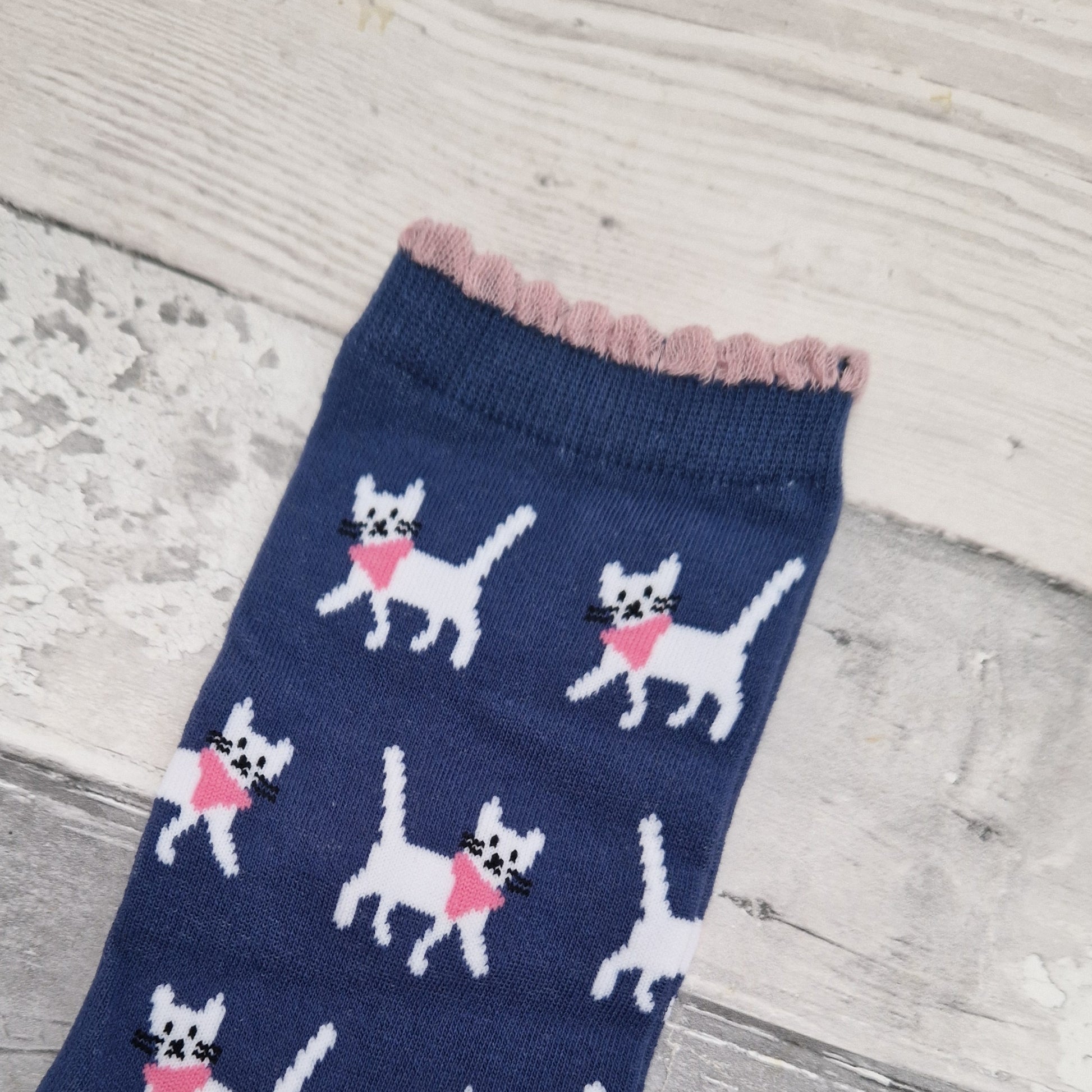Navy blue sock with white cat pattern on a wooden surface
