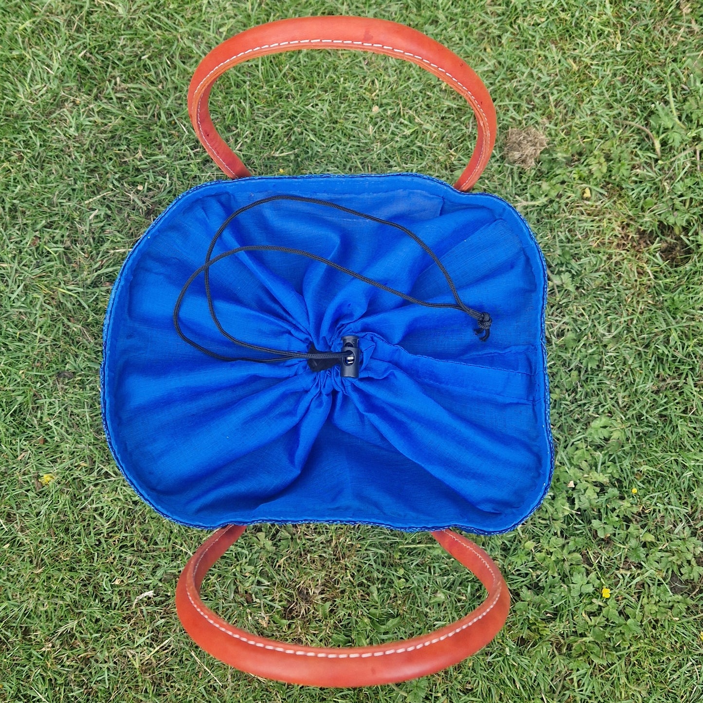 Top down view of a royal blue raffia basket with a closed drawstring top.