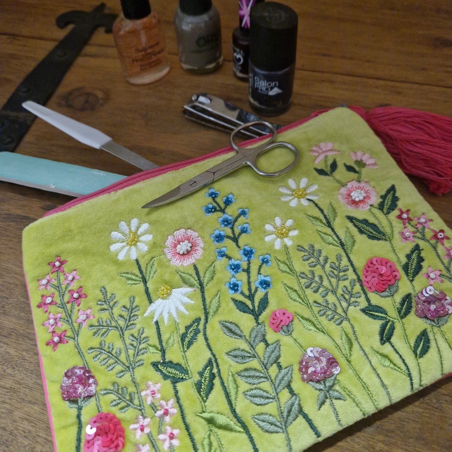 Lime coloured velvet pouch embroidered pouch being used to keep nail care accessories in.