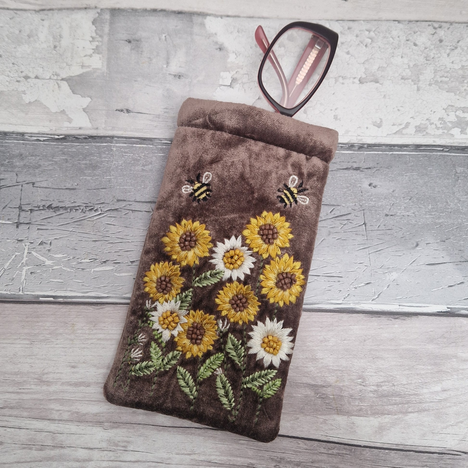 Brown coloured velvet glasses case decorated with embroidered sun flowers and bees. Finished with hand sewn beads.
