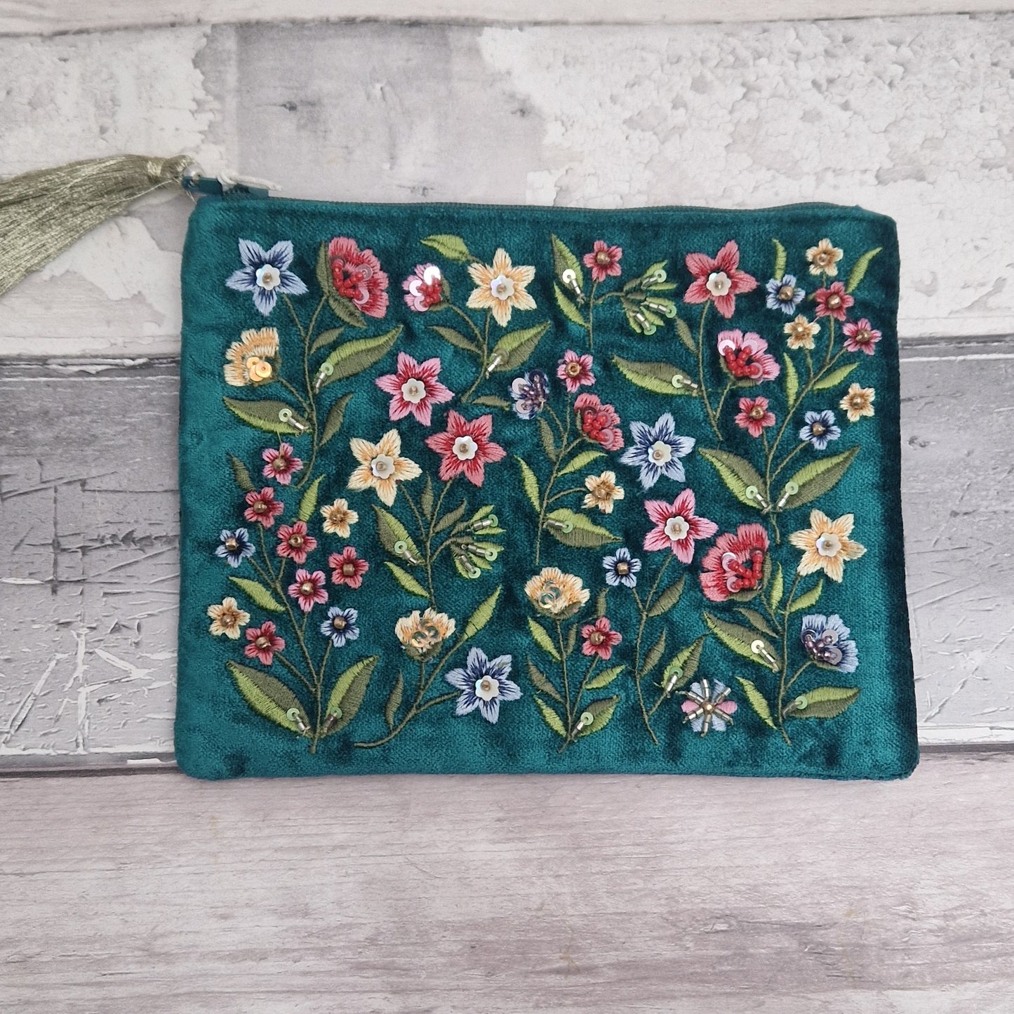Turquoise coloured velvet pouch decorated with embroidered wildflowers in red, yellow and blue on green stems. Finished with hand sewn sequins and beads.
