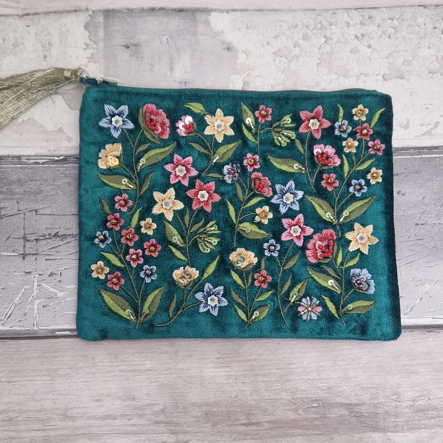 Turquoise coloured velvet pouch decorated with embroidered wildflowers in red, yellow and blue on green stems. Finished with hand sewn sequins and beads.