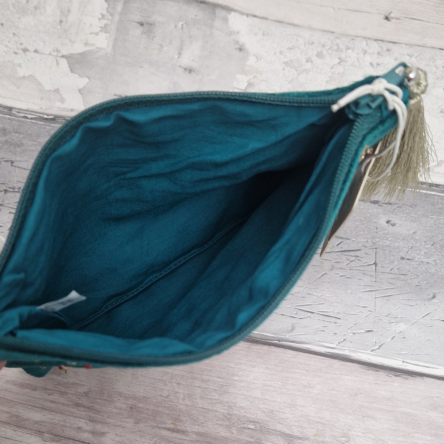 Turquoise coloured velvet pouch decorated with embroidered wildflowers in red, yellow and blue on green stems. Finished with hand sewn sequins and beads.