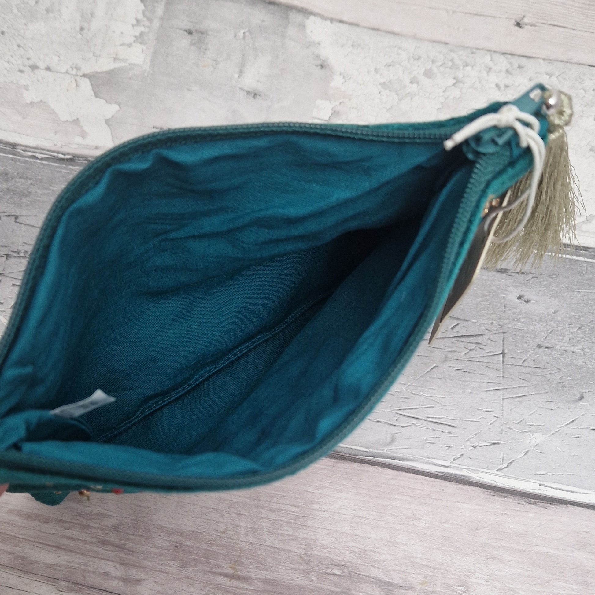 Turquoise coloured velvet pouch decorated with embroidered wildflowers in red, yellow and blue on green stems. Finished with hand sewn sequins and beads.