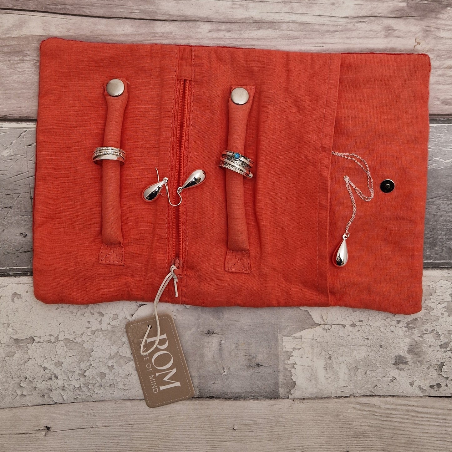 Inside view of an open jewellery roll with silver jewellery ready for storage.