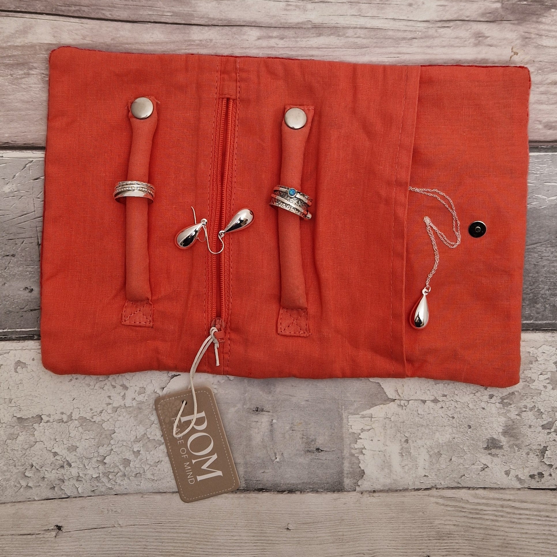 Inside view of an open jewellery roll with silver jewellery ready for storage.