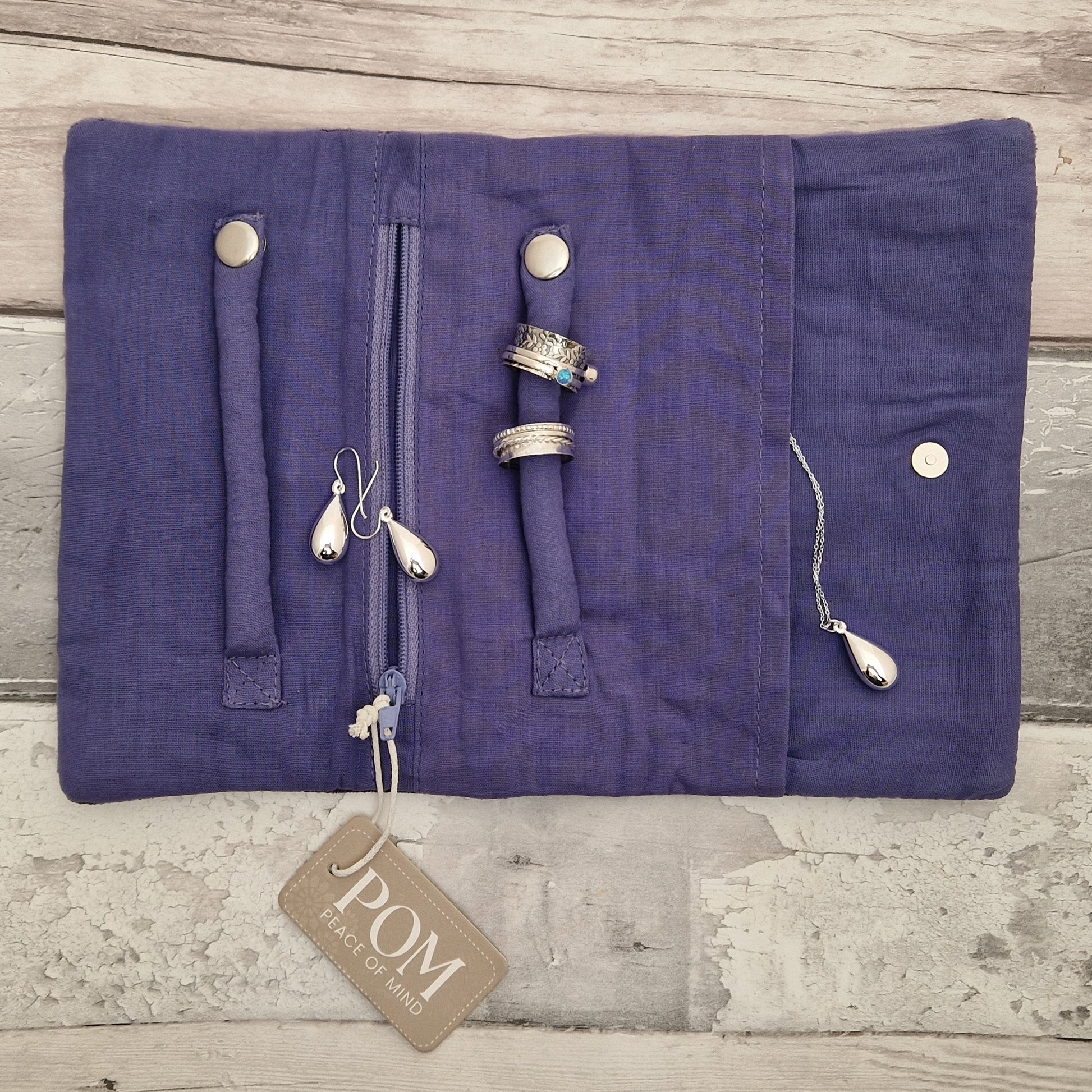 Inside view of an open jewellery roll showing a collection of silver jewellery ready for storage.