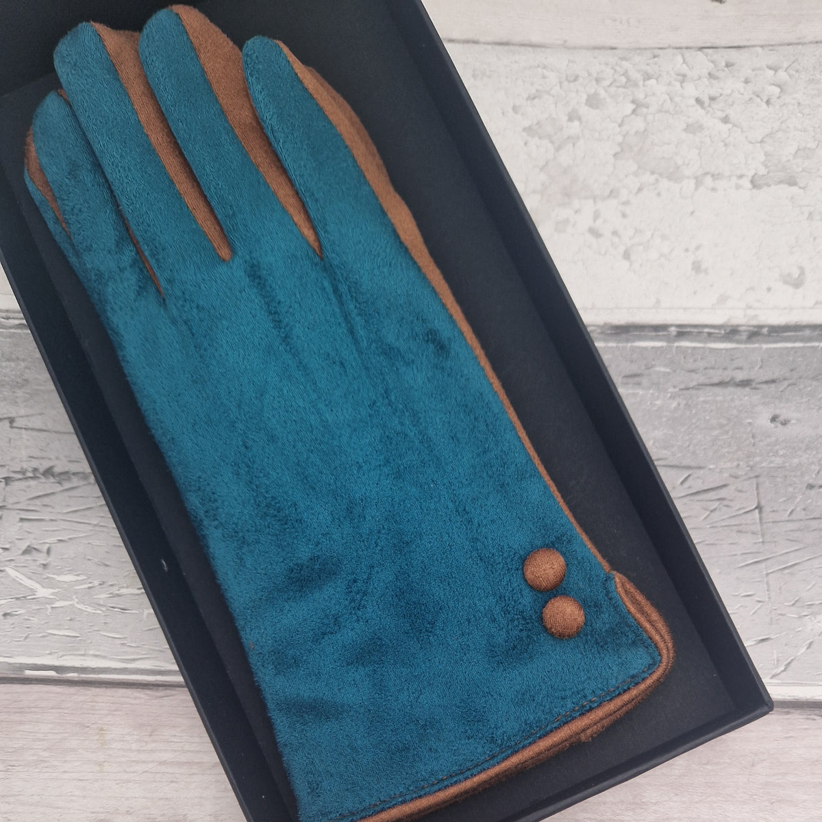 Turquoise and cinnamon coloured gloves with cinnamon buttons presented in a black gift box.