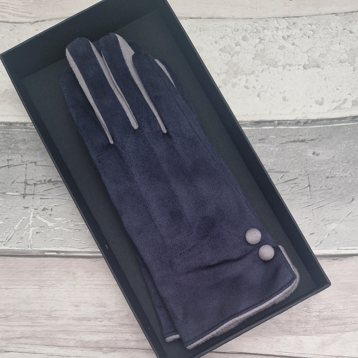Navy and grey coloured gloves with grey buttons presented in a black gift box.