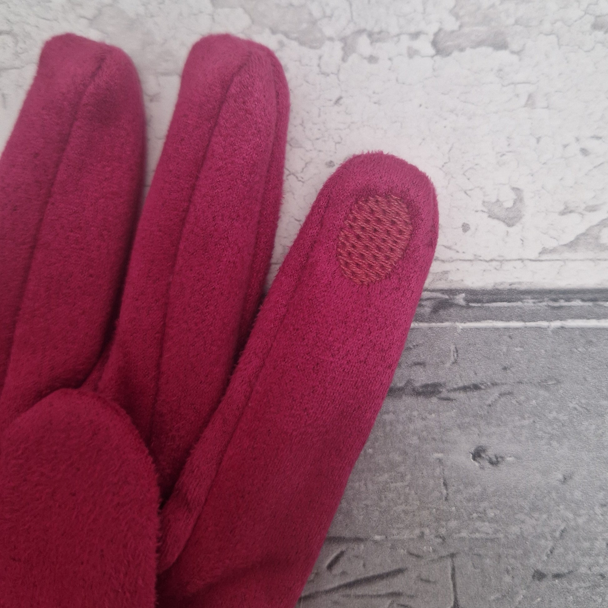 Hot Pink coloured glove with a textured touch screen tip on a gray surface