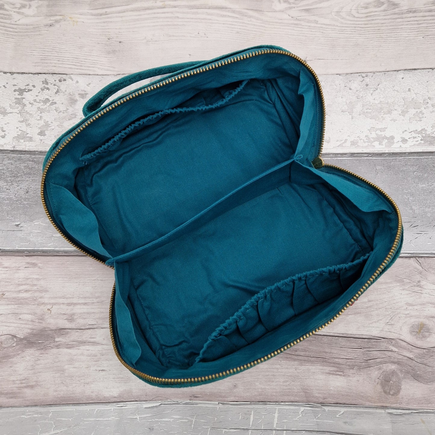 Inside view of fold open vanity case showing a turquoise cotton lining and pockets.