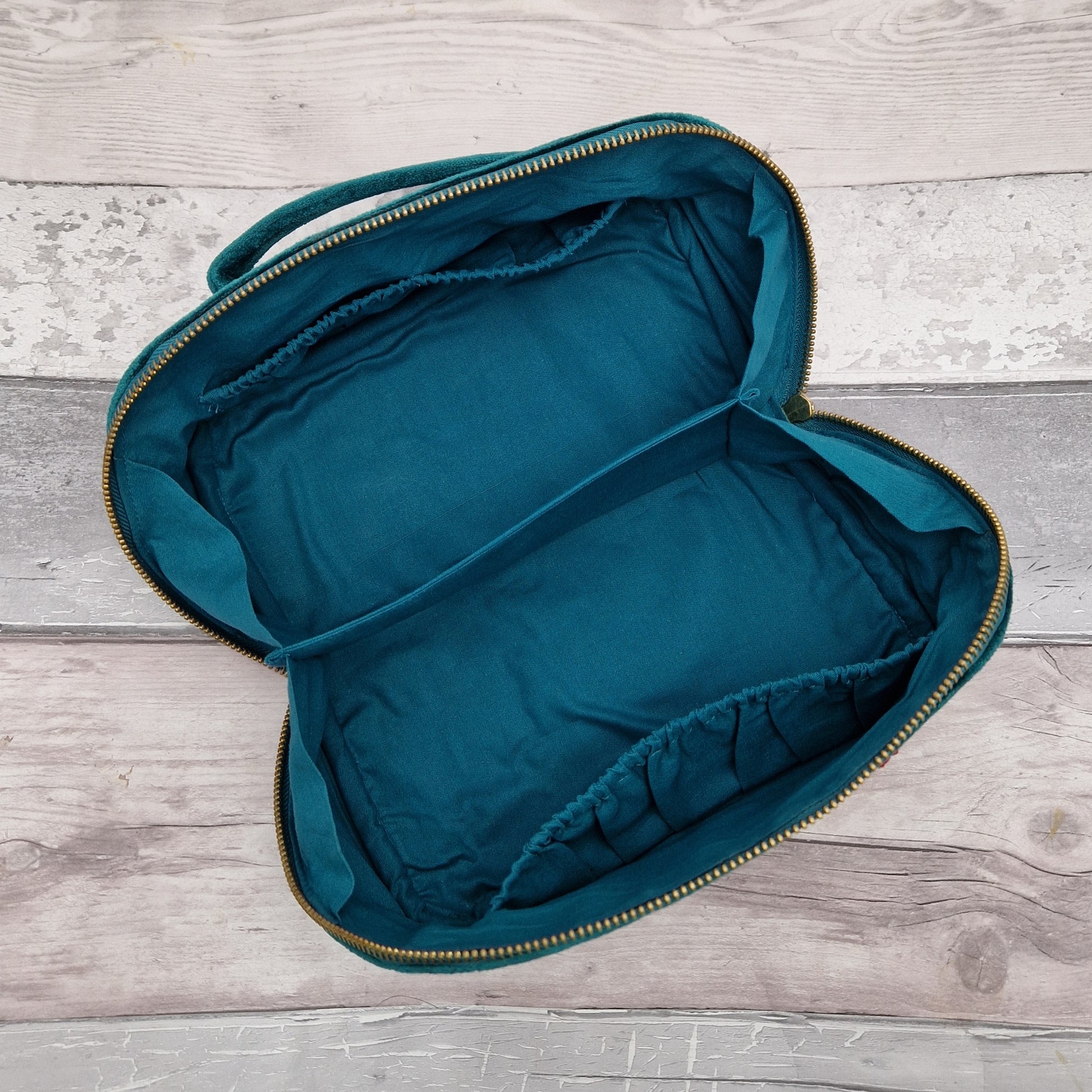 Inside view of fold open vanity case showing a turquoise cotton lining and pockets.