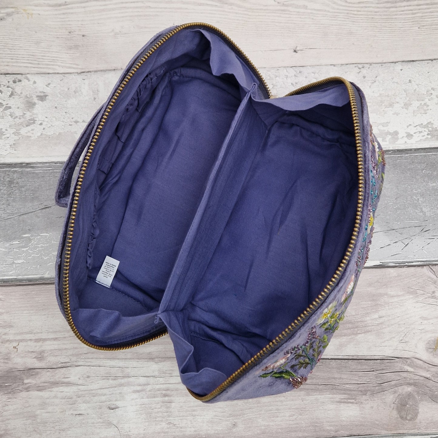 Empty vanity case open to show interior in purple cotton linnning.