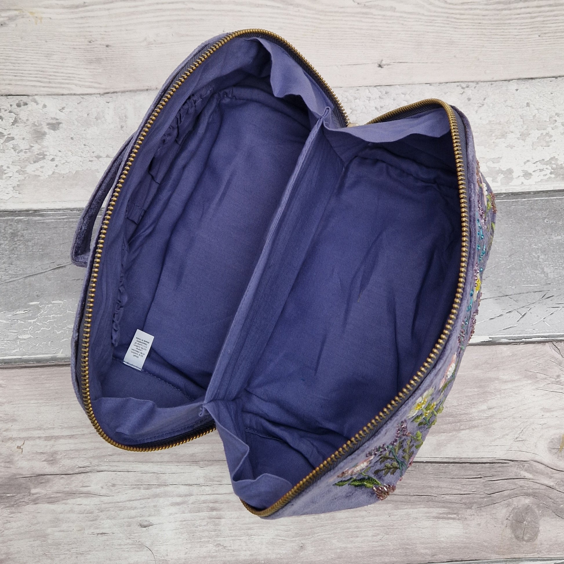 Empty vanity case open to show interior in purple cotton linnning.