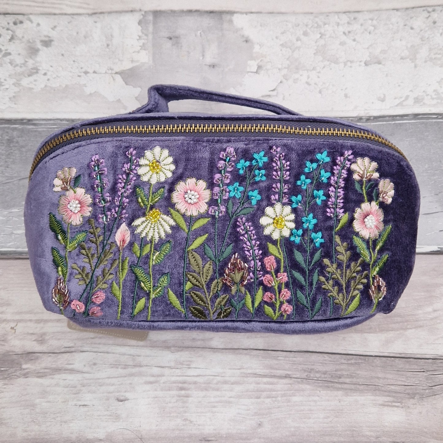 Vanity case with an Embroidered floral design on purple velvet .
