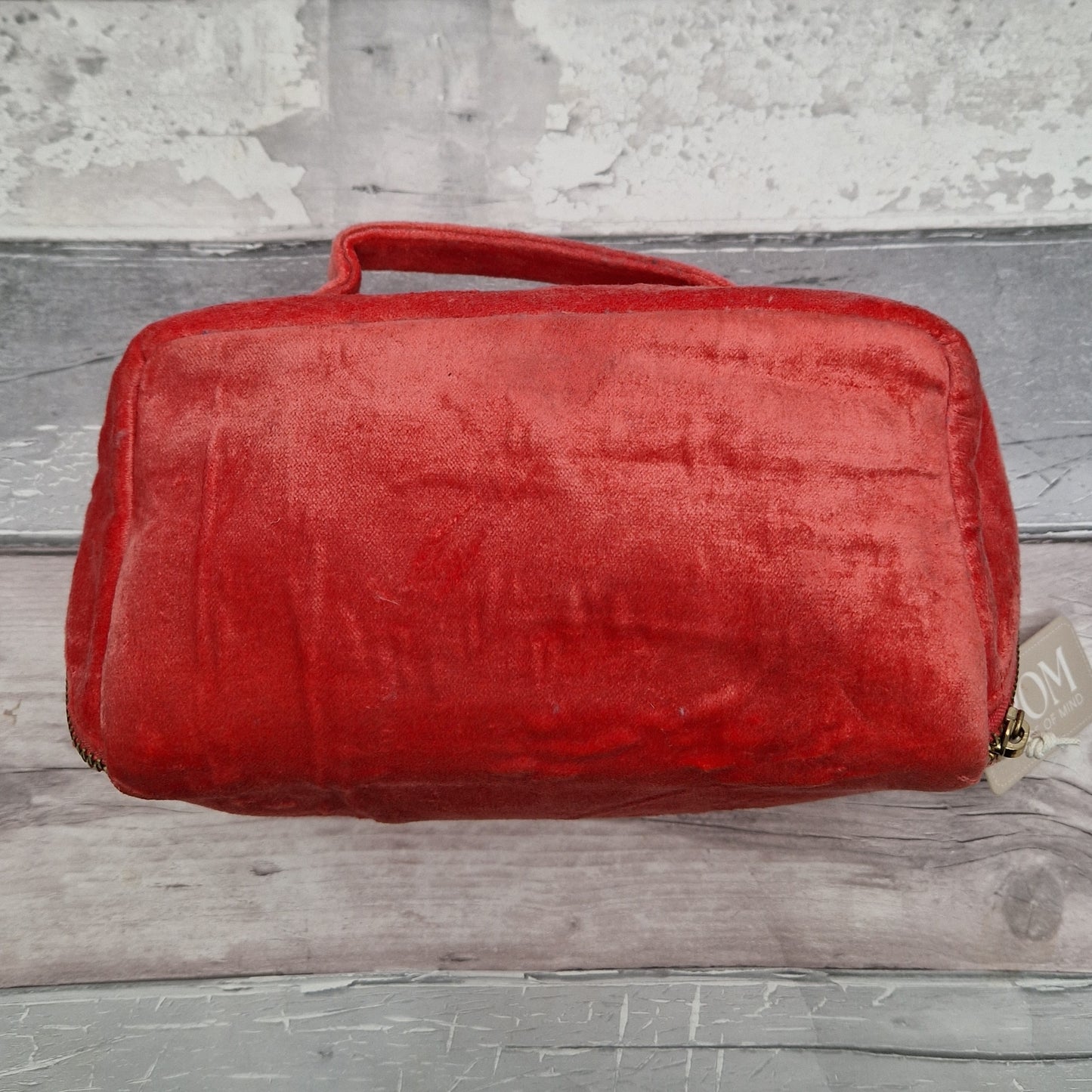 Back view of a salmon coloured velvet vanity case with top handle.