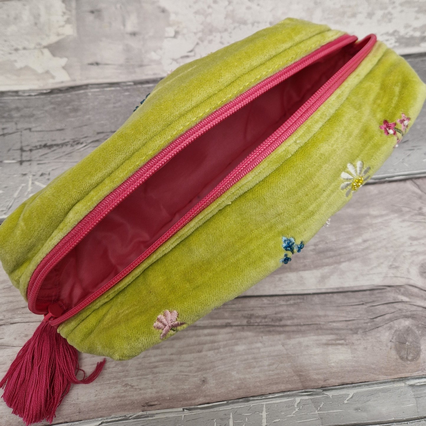 Inside view of a lime green velvet toiletry bag with a waterproof pink internal lining. Matching pink zip and tassel pull.
