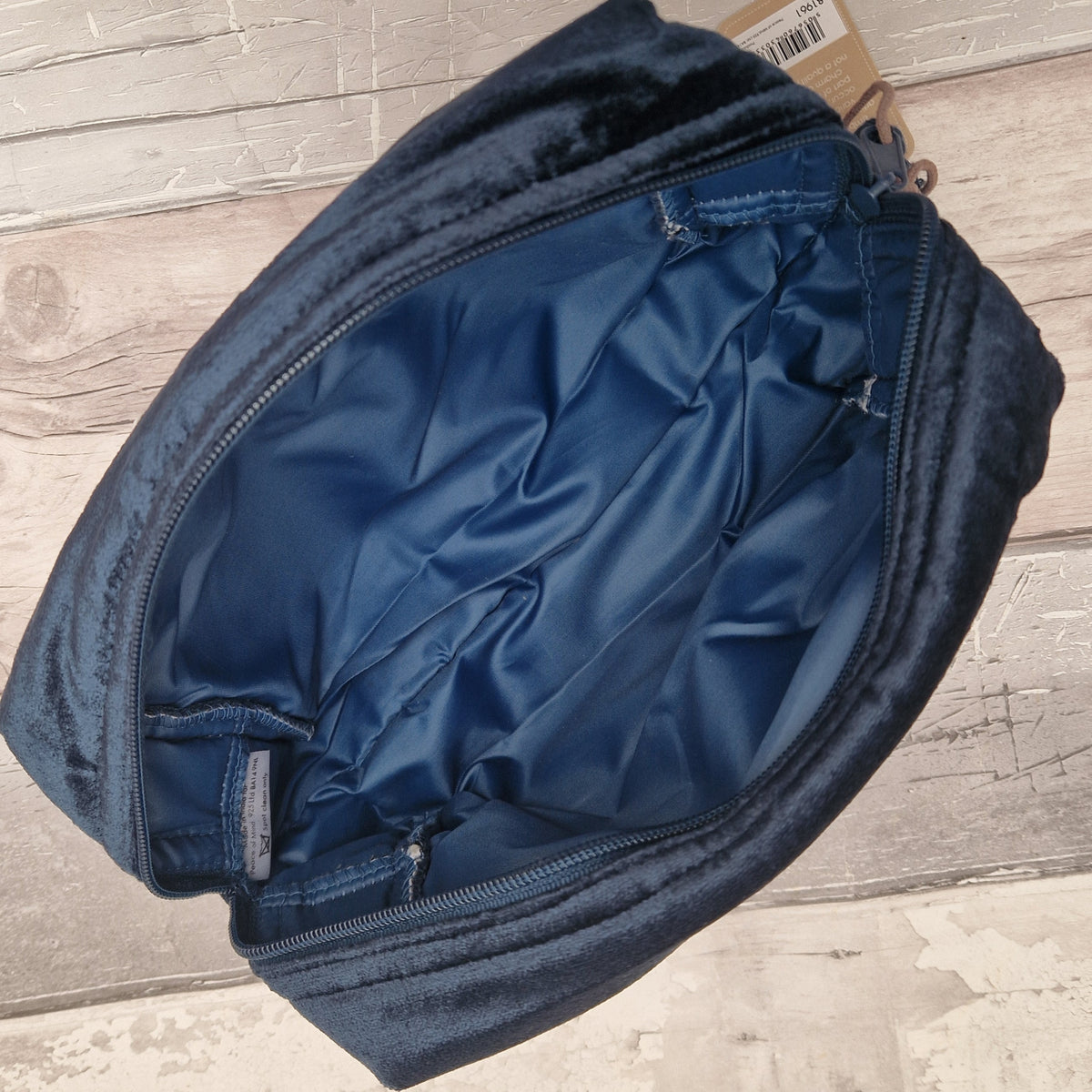 View of open blue velvet wash bag showing a waterproof matching blue interior.