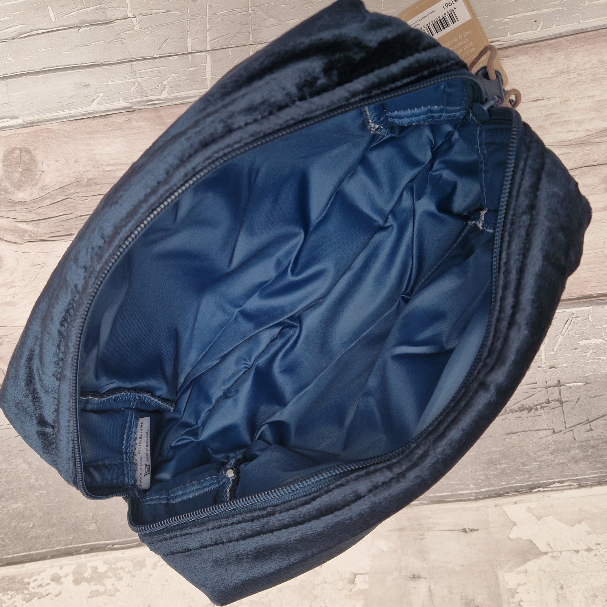 View of open blue velvet wash bag showing a waterproof matching blue interior.
