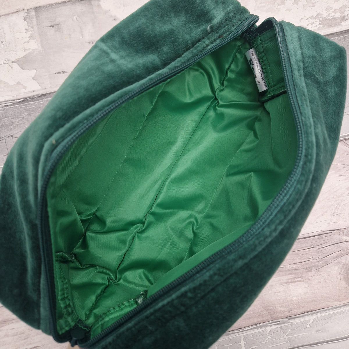 Interior view of a green velvet washbag revealing a matching green waterproof lining.