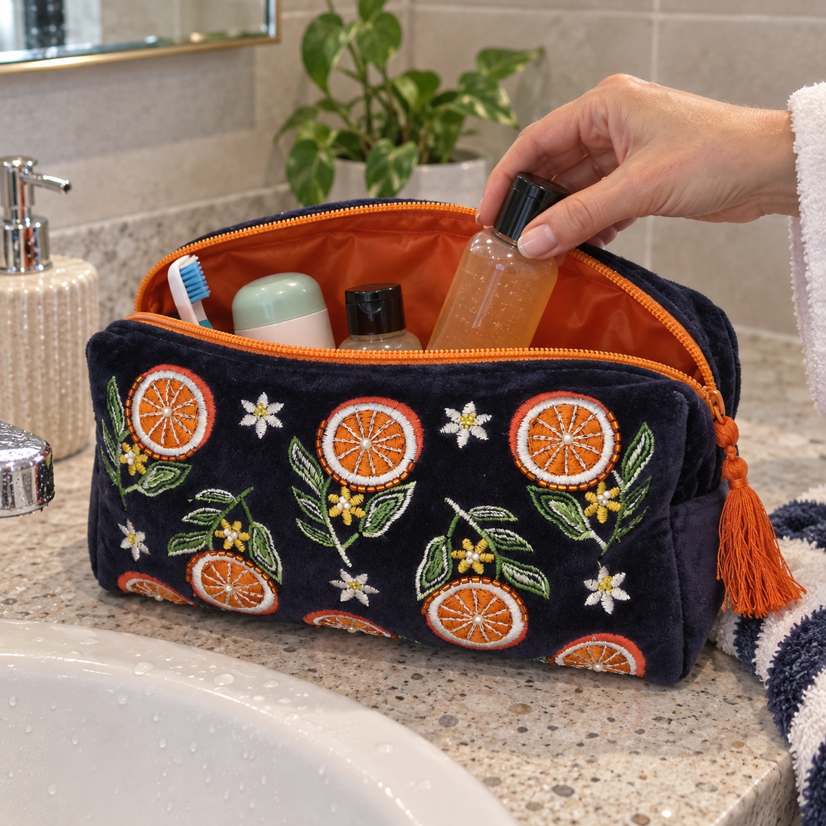 Navy Blue Velvet wash bag decorated with embroidered slices of Orange in a bathroom setting.