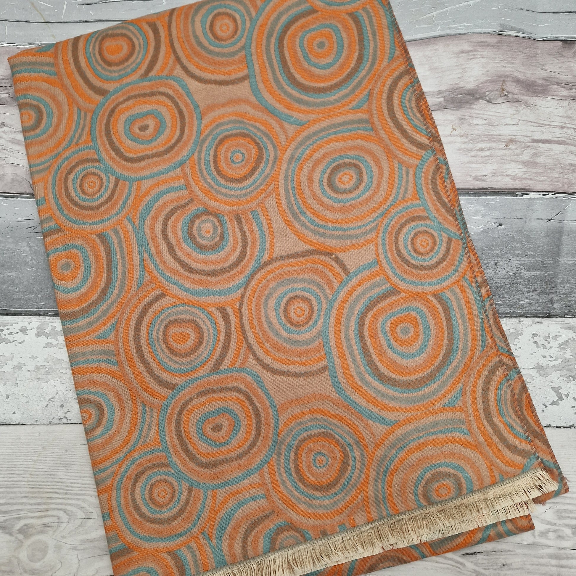 Wool mix scarf decorated with circles in shades of orange, brown and turquoise.