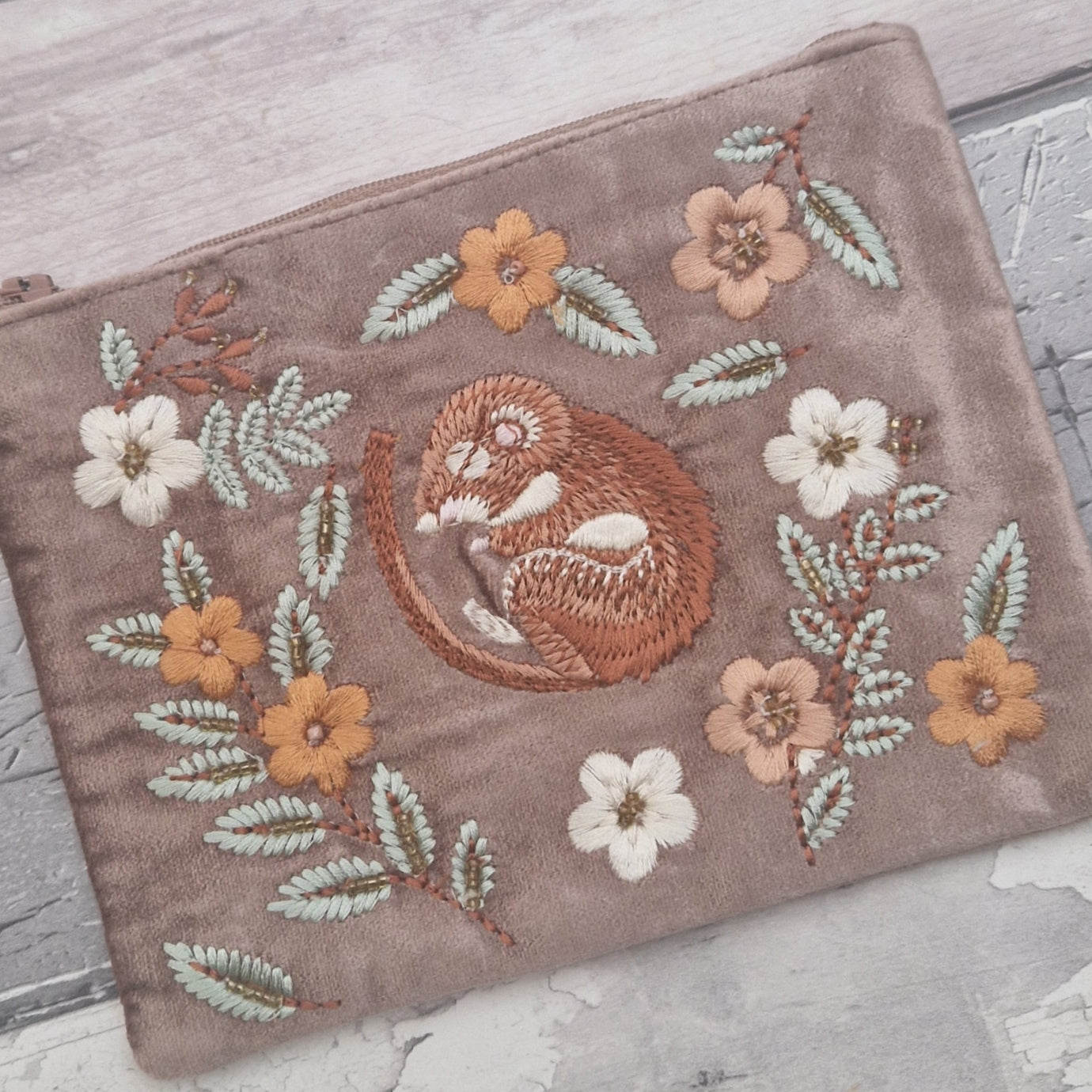 Buff velvet coloured pouch decorated with an embroidered image of a sleeping dormouse surrounded by leaves and flowers.