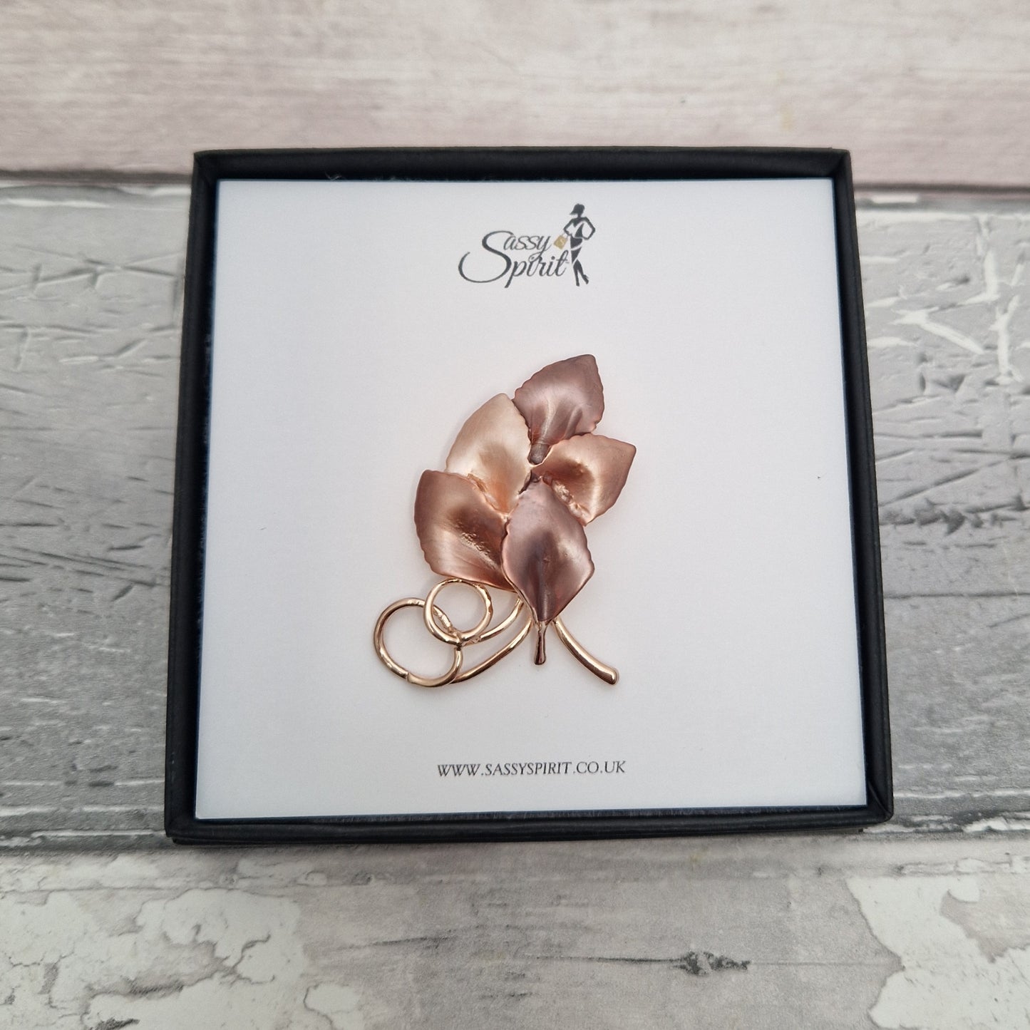 Rose gold leaf-shaped brooch on a branded display card with 'Sassy Spirit' logo.