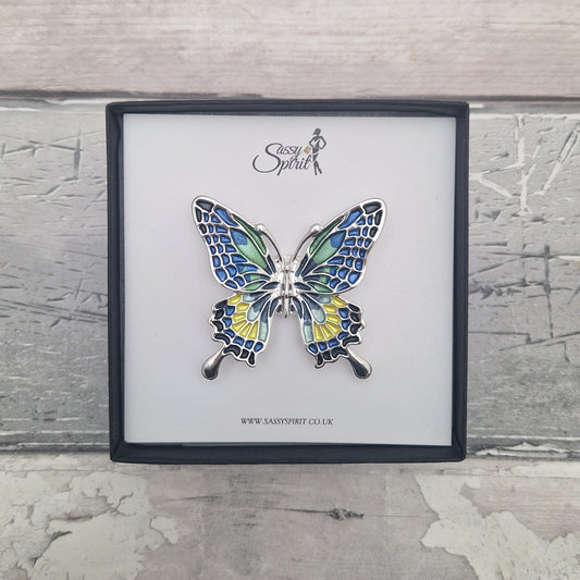 Butterfly-shaped brooch in a black gift box with 'Sassy Spirit' branding on a textured grey background.