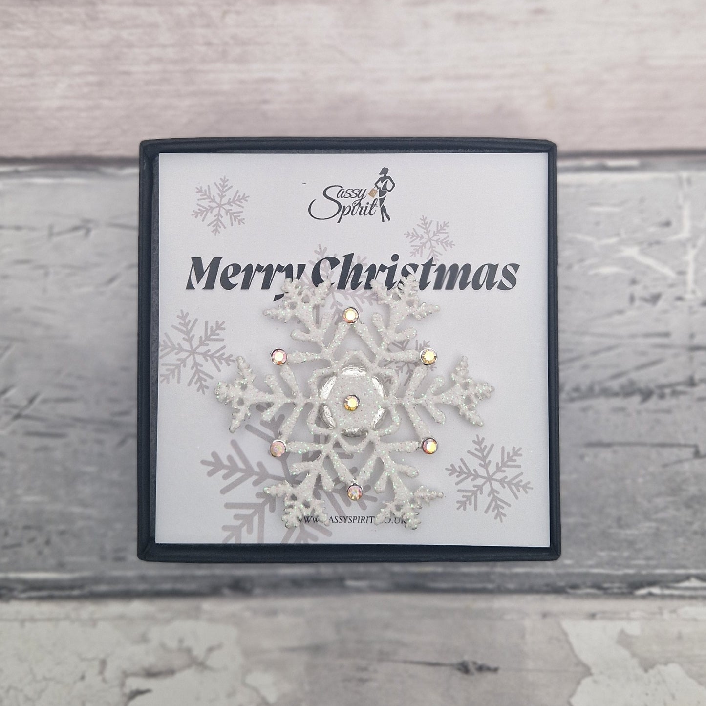 White snowflake magnetic brooch presented in a gift box with a Merry Christmas card.