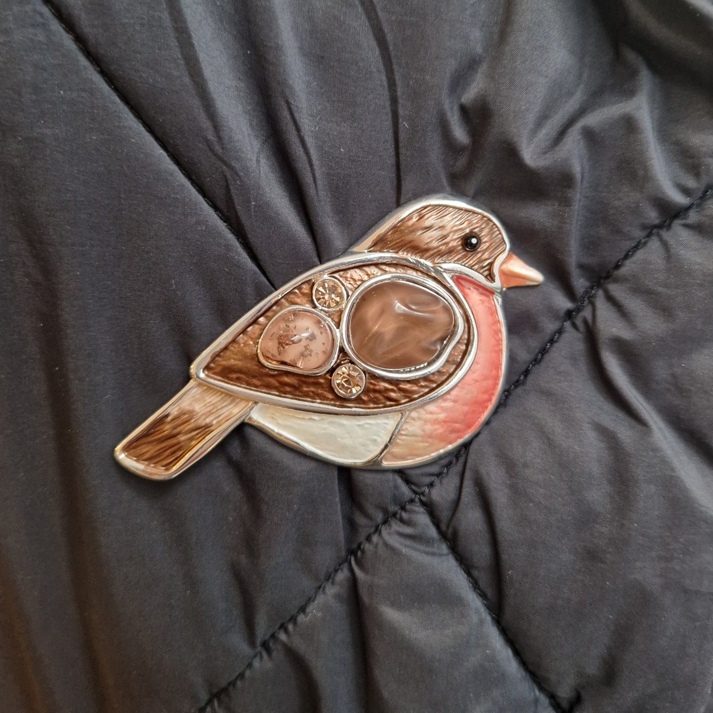 Bird-shaped brooch on a dark quilted fabric background