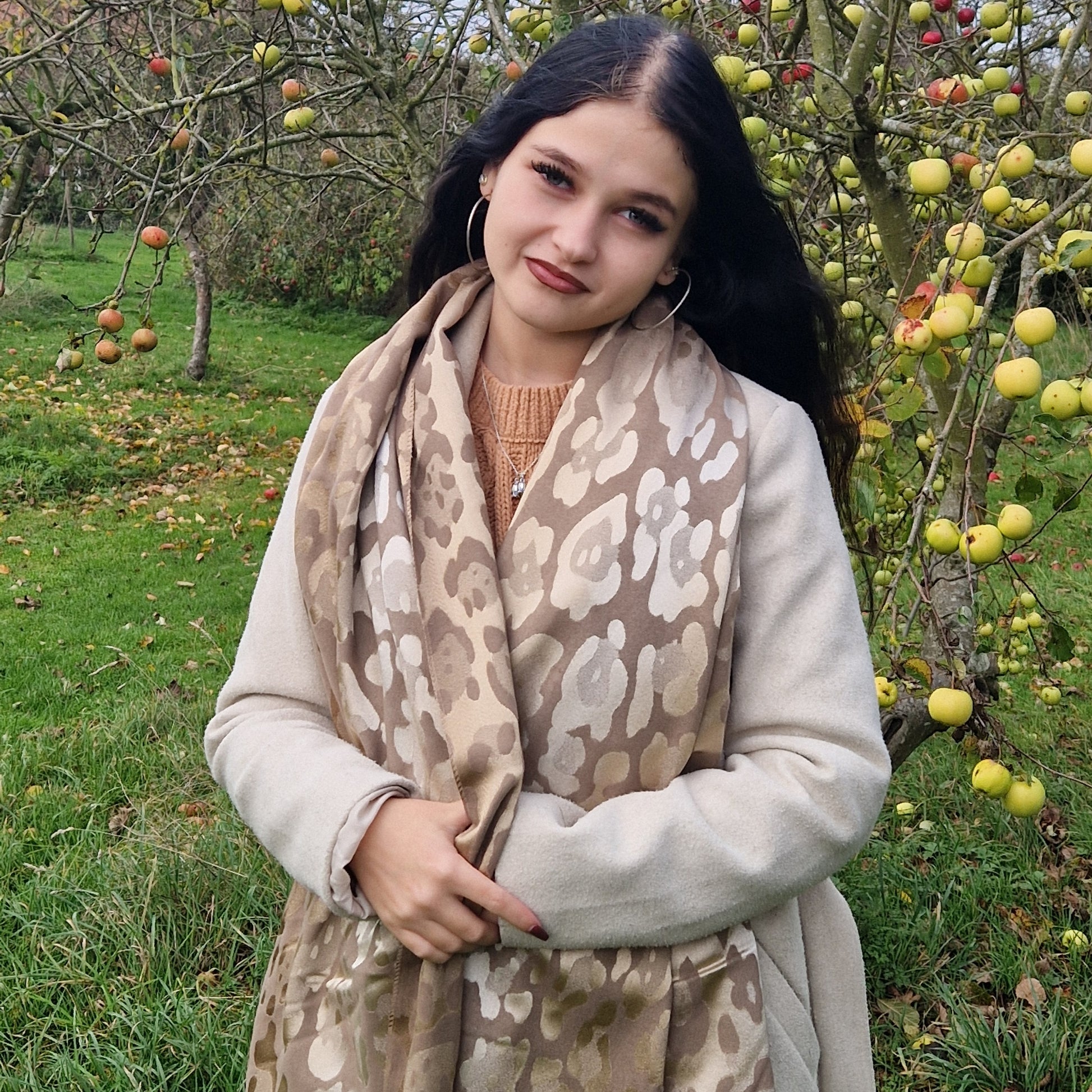 Young woman wearing a brown leopard print scarf in an apple orchard