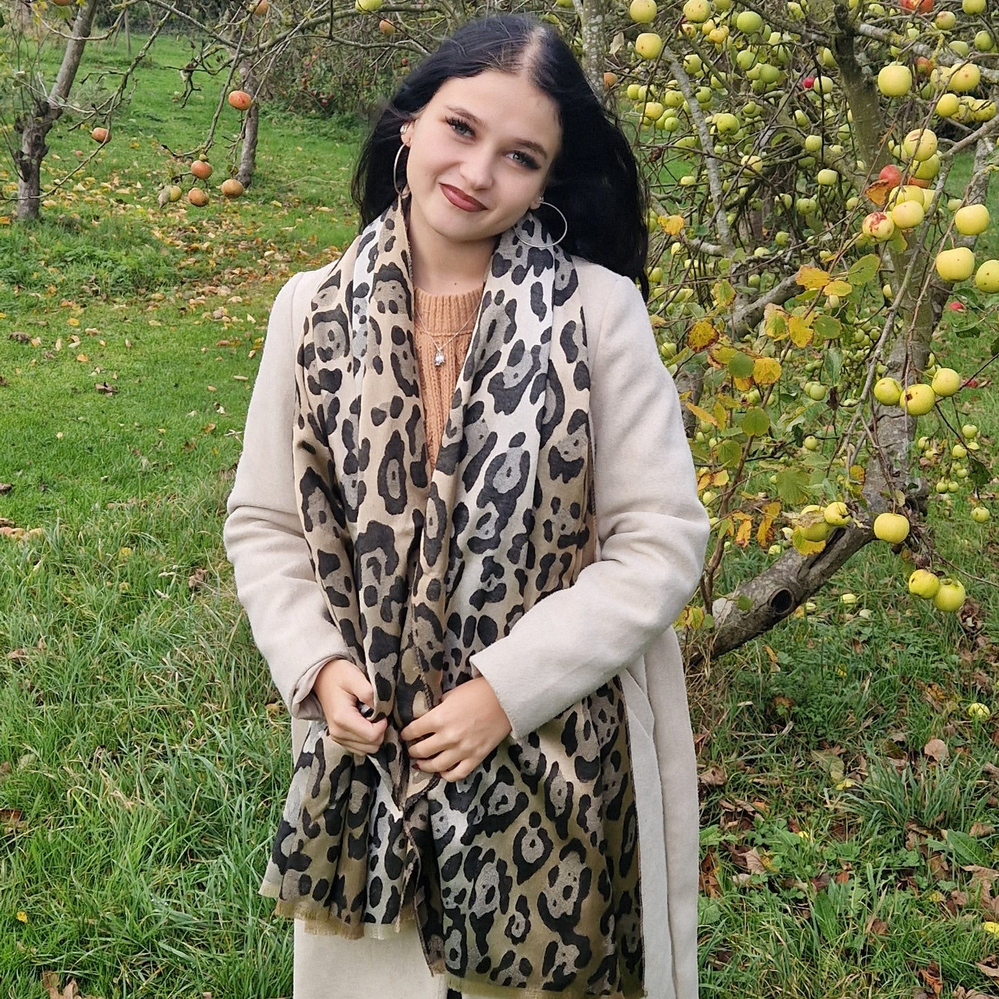 Young Woman wearing a leopard print scarf in an apple orchard