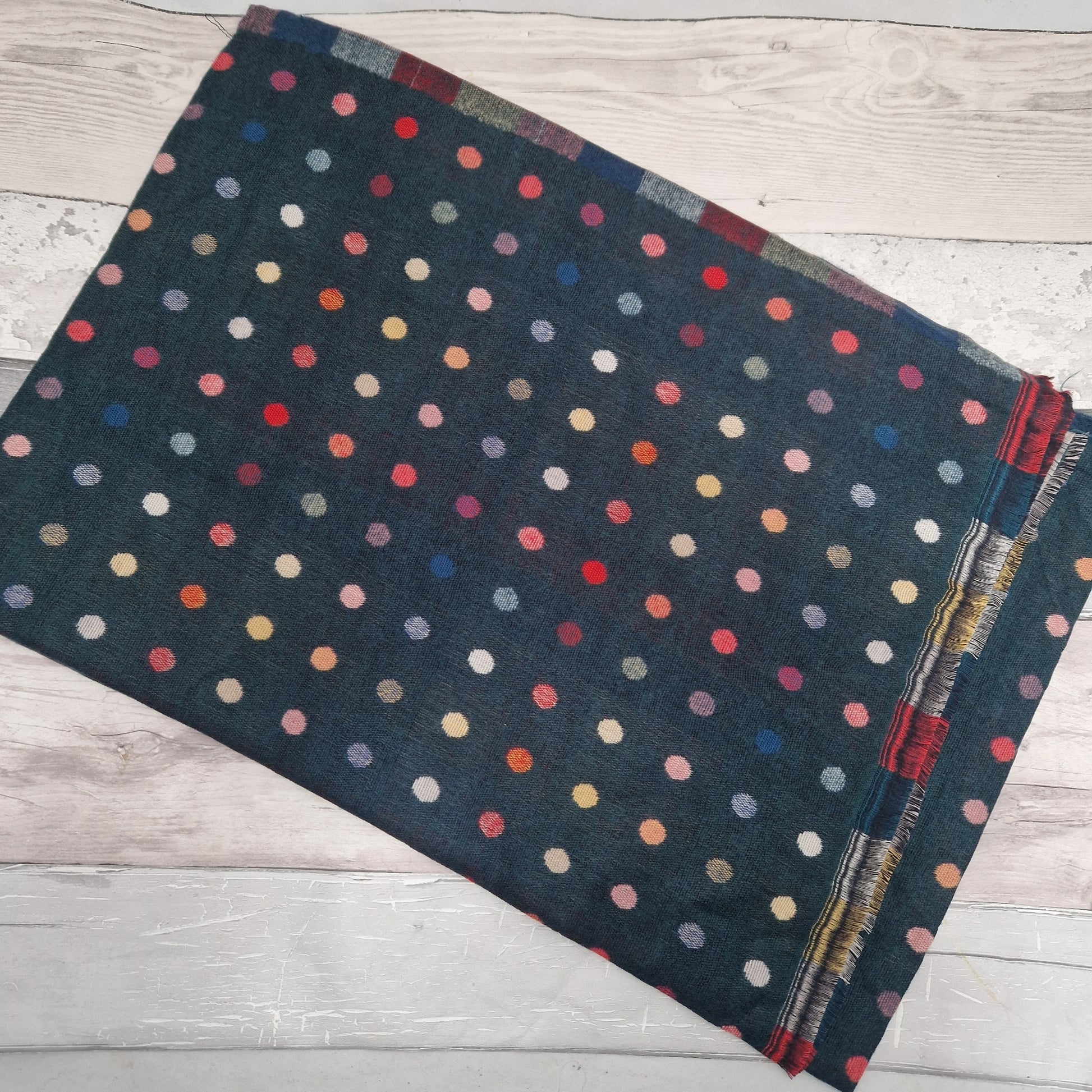 Forest Green Scarf with multicolored polka dot pattern on a wooden surface