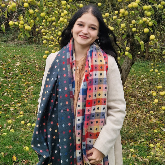 Woman wearing a colorful polka dot scarf in an outdoor setting with trees and apples.