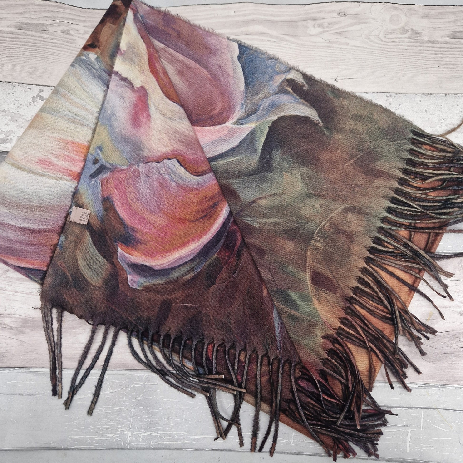 Colorful scarf with fringes on a wooden surface