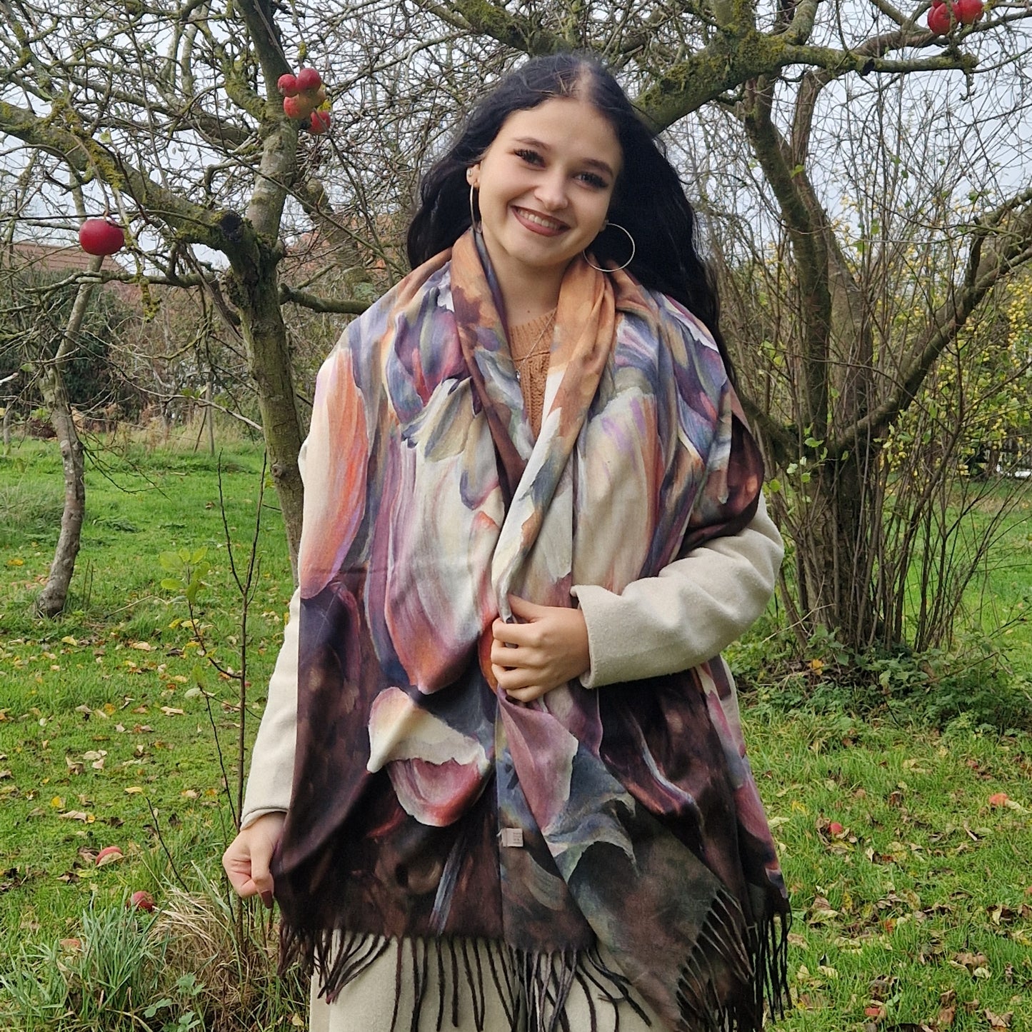 Young Woman wearing a colorful scarf in an outdoor setting with trees and grass.