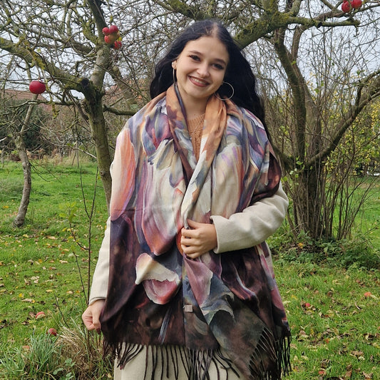 Young Woman wearing a colorful scarf in an outdoor setting with trees and grass.